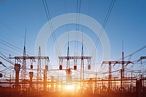 Distribution electric substation with power lines and transformers, at sunset