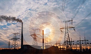 Distribution electric substation with power lines and transformers, at sunset