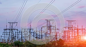 Distribution electric substation with power lines and transformers, at sunset