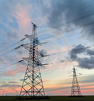 Distribution electric substation with power lines and transformers, at sunset