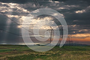 Distribution pylons with high voltage wires at sunrise