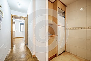 Distributor corridor of a house with an oak wooden corridor, access to a small kitchen with light wood furniture and a white