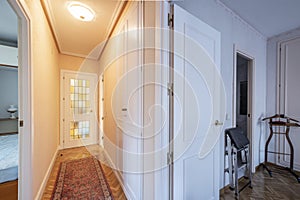 Distributor corridor of an urban residential house with white carpentry with leaded windows and parquet floors with narrow rugs