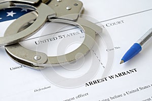 District Court Arrest Warrant court papers with handcuffs and blue pen on United States flag. Concept of permission to arrest photo