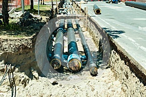 District heating pipeline reparation and reconstruction parallel with the street with construction site safety net fence.