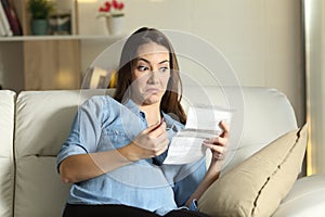 Distrustful pregnant lady reading a leaflet before take a pill