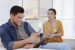 Distrustful woman peering into boyfriend`s smartphone. Jealousy in relationship