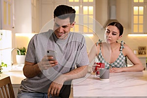 Distrustful woman peering into boyfriend`s smartphone. Jealousy in relationship