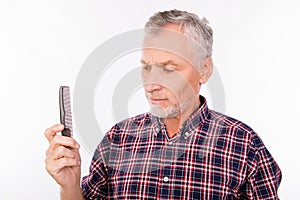 Disturbed aged man holding a comb