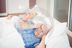 Disturbed man covering ears from snoring wife