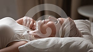 Disturbed mature older woman lying awake in uncomfortable bed