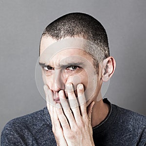 Disturbed unhappy man putting hands on cheeks for suspicion