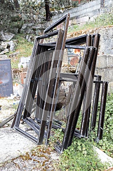 Disused aluminum window frames stacked outside the house.