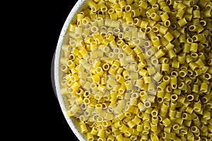 Ditalini pasta in a bowl on a black background