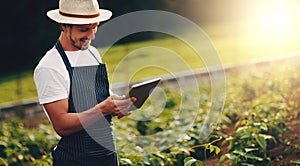 Ditching the gardeners manual and going digital. a young man using a digital tablet while working in a garden.