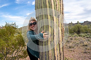 Ditzy blonde woman gives a Saguaro cactus a hug