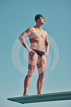 Dive right in. Full length shot of a handsome young male athlete standing on a diving board outside.