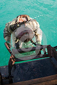 Diver in an diving suit immerses in water