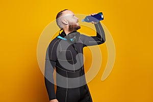 Diver drinking on bright studio wall background