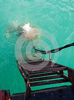 Diver in old diving suit immerses in water photo