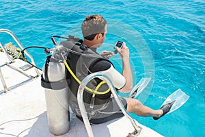 Diver preparing to dive into the ocean from a yacht with his underwater camera