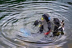 The diver is ready to dive into the water. A man in a wetsuit and scuba gear is ready to dive the cold water of a forest