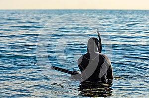 Scuba diver with spear gun ready to go underwater and spearfishing - sea landscape at sunset photo