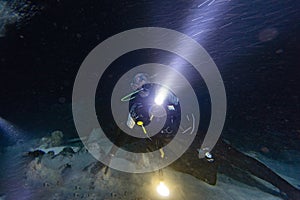 Diver in strong current at night with torch