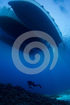 Scuba Diver below boat underwater scene