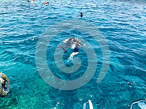 Divers in black diving waterproof suits with shiny metal aluminum cylinders float, immersed in blue sea water on vacation, sea cru