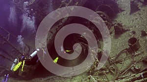 Divers near wreck ship underwater on coral reef Abu Nuhas in Red sea.