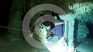 Divers in rocks of underwater cave Yucatan Mexico cenotes.