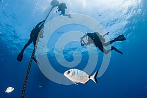 Divers under boat for deco time in the blue