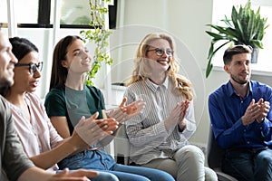 Diverse audience of different aged employees applauding presenter