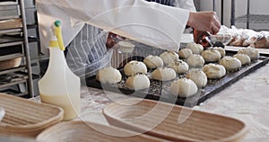 Diverse bakers working in bakery kitchen, sprinkling poppy seeds on rolls in slow motion