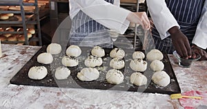 Diverse bakers working in bakery kitchen, sprinkling poppy seeds on rolls in slow motion