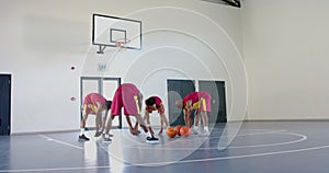 Diverse basketball players practice in an indoor court