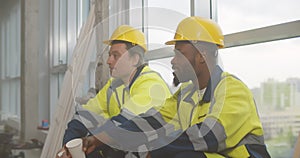 Diverse builders resting and drinking coffee at construction site