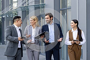 Diverse business colleagues laughing and discussing work outside modern office building