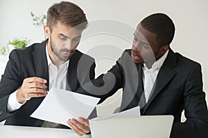Diverse business partners in suits holding documents discussing