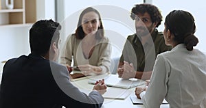 Diverse business partners talking at meeting table, discussing partnership terms