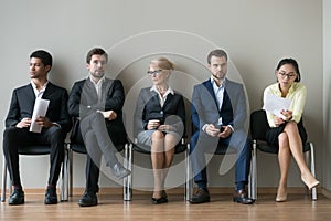 Diverse businesspeople applicants sitting in row waiting for job interview photo