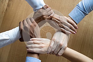 Diverse business people team grasping hands, close up top view