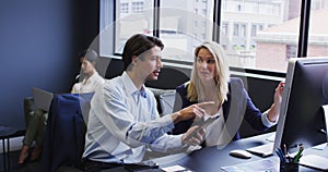 Diverse business people using computer at desk in office