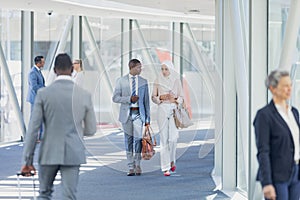 Diverse business people walking in corridor in modern office