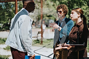 Diverse business team discusses project at an outdoor meeting on a sunny day in the city