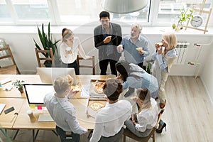 Diverse business team eating pizza together in office, top view