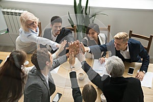 Diverse business team giving high five showing unity, top view