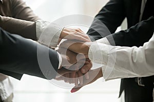 Diverse business team holding pile of hands promising loyalty, c