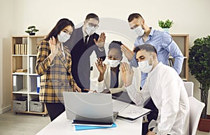 Diverse business team in protective masks having video conference on laptop